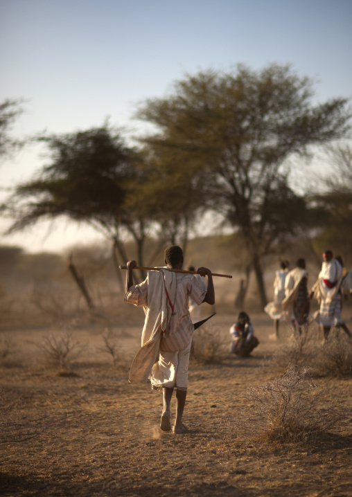 Rear View Of A Karrayyu Tribe Teenage Boy With A Gilee Dagger Holding A Stick During Gadaaa Ceremony, Metahara, Ethiopia