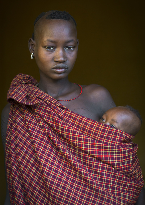 Portrait Of A Bodi Tribe Mother Carrying Her Baby, Hana Mursi, Omo Valley, Ethiopia