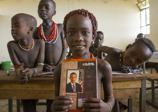 Hamer Tribe Girl Holding A Book With Barack Obama On The Cover In A School, Turmi, Omo Valley, Ethiopia