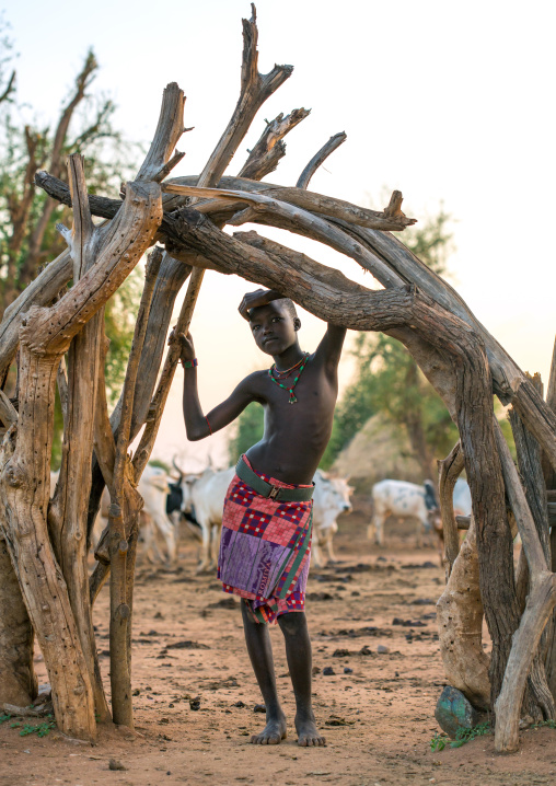 Hamer tribe boy standing at a wooden doorway, Omo valley, Turmi, Ethiopia