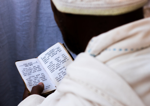 Ethiopian orthodox man praying with a bible, Amhara region, Lalibela, Ethiopia