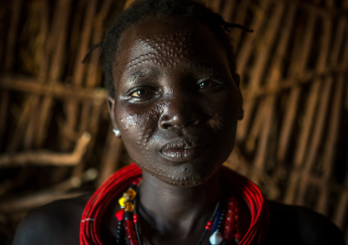 Toposa tribe woman with scarified face and red necklaces, Omo valley, Kangate, Ethiopia