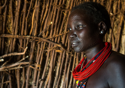 Toposa tribe woman with scarified face and red necklaces, Omo valley, Kangate, Ethiopia