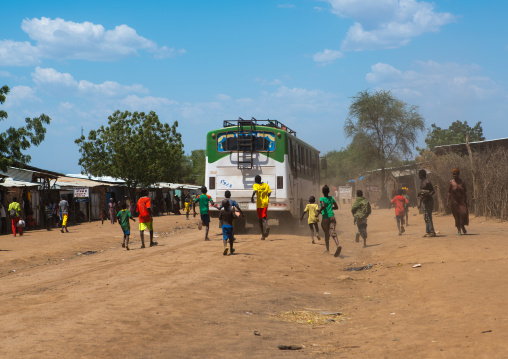 Children running after a bus on a dusty road, Omo valley, Kangate, Ethiopia