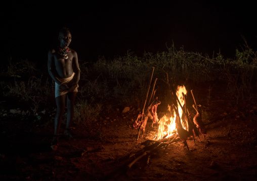 Hamer tribe teenage boy cooking a bbq goat, Omo valley, Turmi, Ethiopia