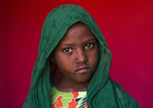 Portrait of an afar tribe girl on a red background, Afar region, Semera, Ethiopia