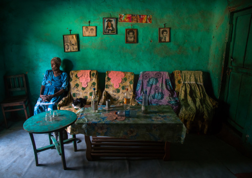 Old woman inside her house decorated with old pictures of her relatives, Omo valley, Jinka, Ethiopia