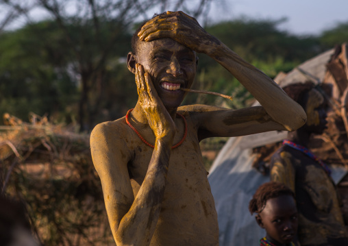 Dassanech man putting mud on his body during dimi ceremony to celebrate circumcision of the teenagers, Omo valley, Omorate, Ethiopia