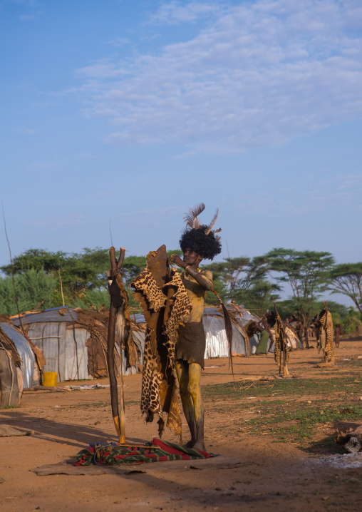 Dassanech man dressing with a leopard skin for dimi ceremony to celebrate circumcision of the teenagers, Omo valley, Omorate, Ethiopia