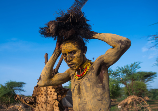 Dassanech man dressing with an ostrich feathers headwear for dimi ceremony to celebrate circumcision of the teenagers, Omo valley, Omorate, Ethiopia