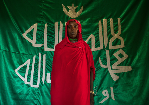 Sufi woman worshipper in front of islamic green flag, Harari region, Harar, Ethiopia