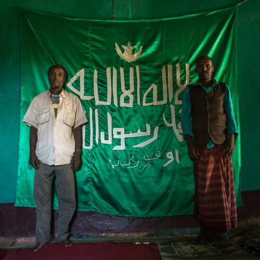 Sufi men worshippers in front of islamic flag, Harari region, Harar, Ethiopia