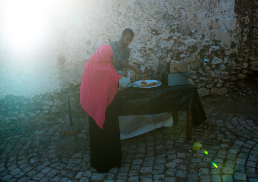 Woman buying samosas in the street, Harari region, Harar, Ethiopia