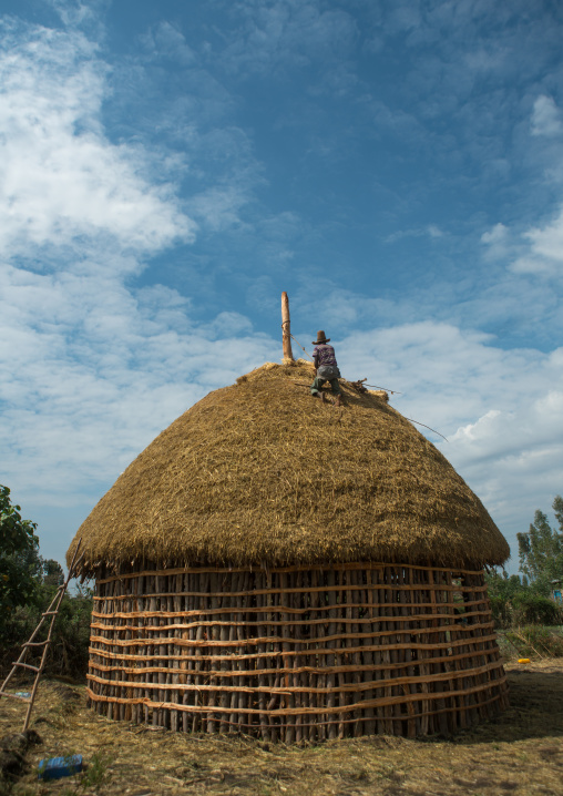 Man covers the thatched roof of a traditional ethiopian house, Kembata, Alaba kuito, Ethiopia