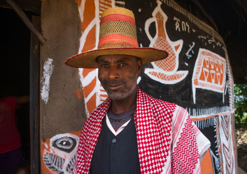 Ethiopia, Kembata, Alaba Kuito, ethiopian muslim man with a hat standing in front of his traditional painted house