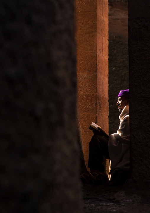 Lonely ethiopian orthodox man praying with a bible, Amhara region, Lalibela, Ethiopia