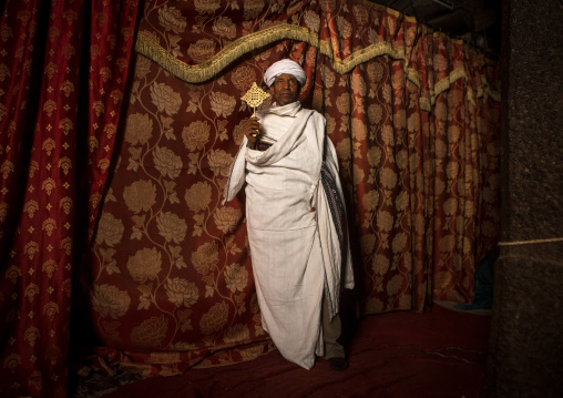 Ethiopian orthodox priest holding a cross inside a rock church, Amhara region, Lalibela, Ethiopia