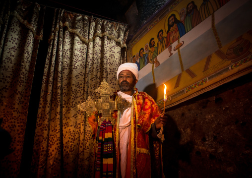 Ethiopian orthodox priest holding a cross inside a rock church, Amhara region, Lalibela, Ethiopia