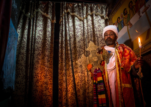 Ethiopian orthodox priest holding a cross inside a rock church, Amhara region, Lalibela, Ethiopia