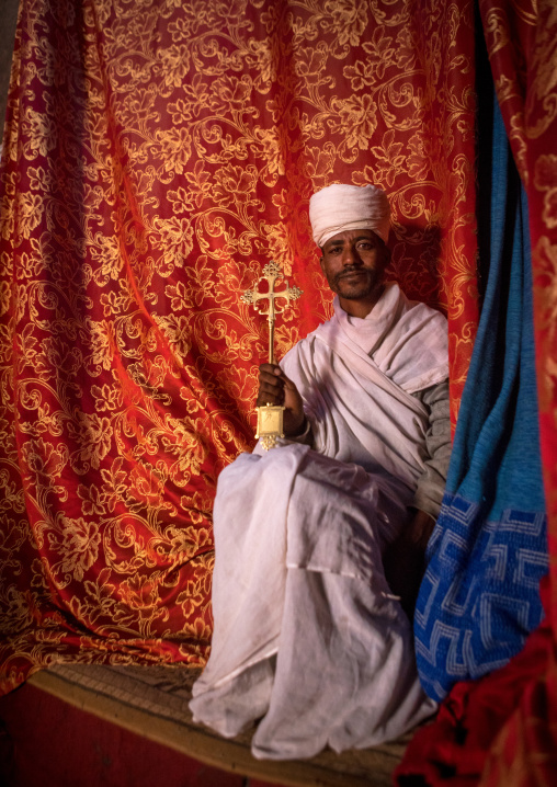 Ethiopian orthodox priest holding a cross inside a rock church, Amhara region, Lalibela, Ethiopia