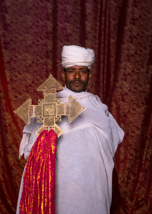 Portrait of an ethiopian orthodox priest holding a cross inside a rock church, Amhara region, Lalibela, Ethiopia