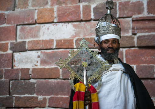 Ethiopian orthodox priest holding a cross inside nakuto lab rock church, Amhara region, Lalibela, Ethiopia