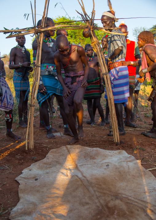 Hamer tribe men passing thru a symbolic door during a bull jumping ceremony, Omo valley, Turmi, Ethiopia