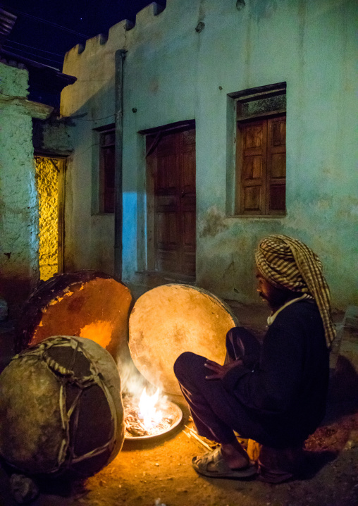 Harari man heating the drums before a ceremony in sufi community, Harari Region, Harar, Ethiopia