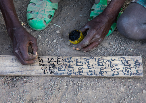 Afar tribe teacher writing on a wood board in a coranic school, Afar region, Afambo, Ethiopia