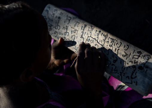 Afar tribe girl writing on a wood board in a coranic school, Afar region, Afambo, Ethiopia