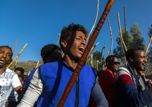 Ethiopian young men dancing and singing in the street with sticks during Timkat epiphany festival, Amhara region, Lalibela, Ethiopia