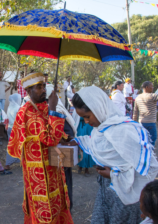 Ethiopian woman giving money to a monk during Timkat epiphany festival, Amhara region, Lalibela, Ethiopia