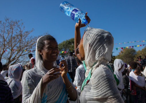 Ethiopian pilgrim woman putting some holy water on her face during Timkat epiphany festival, Amhara region, Lalibela, Ethiopia