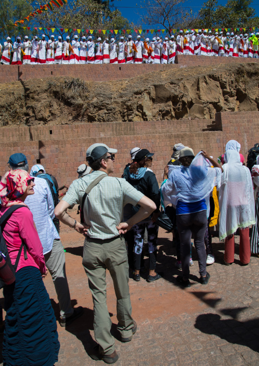 Tourists looking ethiopian orthodox priests celebrating in line the colorful Timkat epiphany festival, Amhara region, Lalibela, Ethiopia