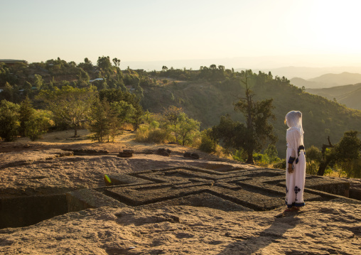 Ethiopian woman standing in front of the monolithic rock-cut church of st. George, Amhara region, Lalibela, Ethiopia