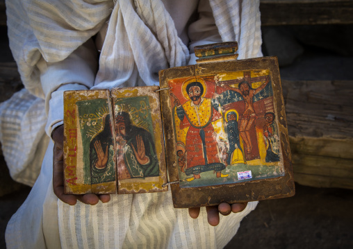 Priest of the ethiopian orthodox church in Asheten mariam rock hewn church holds ancient illuminated icons, Amhara region, Lalibela, Ethiopia