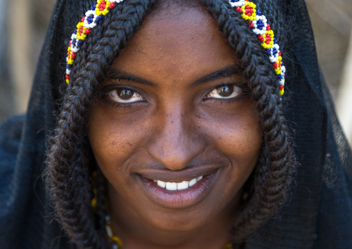 Portrait of a smiling Afar tribe girl with braided hair ands beaded headband, Afar region, Chifra, Ethiopia