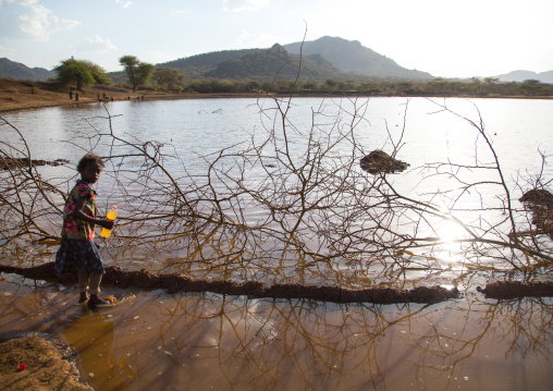 Borana tribe girl filling jerrican in a water reservoir used for animals, Oromia, Yabelo, Ethiopia