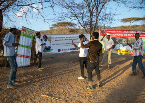 Young men taking pictures in front of HIV billboards during the Gada system ceremony in Borana tribe, Oromia, Yabelo, Ethiopia