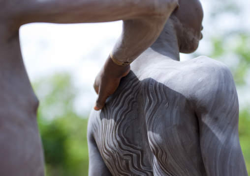 Clay body paintings on Suri warriors before donga stick fighting, Turgit village, Omo valley, Ethiopia