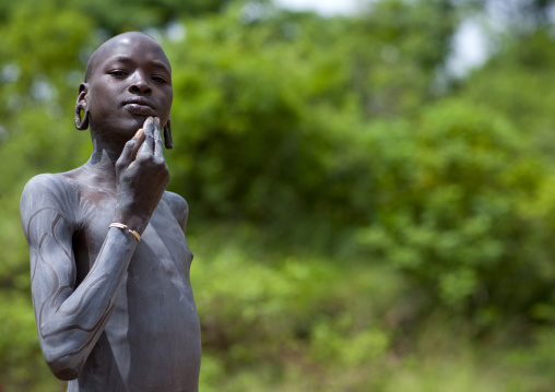 Clay body paintings on Suri warriors before donga stick fighting, Turgit village, Omo valley, Ethiopia