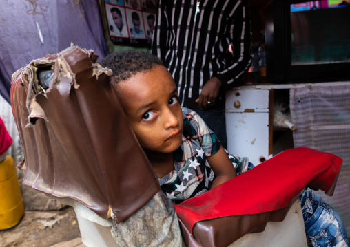 Ethiopian boy sit on a barber seat, Harari region, Harar, Ethiopia