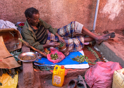 Ethiopian man without teeth crashing some qat in the street, Harari region, Harar, Ethiopia