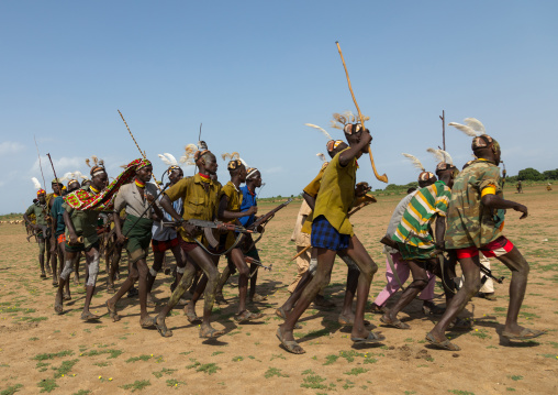 Men running in line with weapons during the proud ox ceremony in the Dassanech tribe, Turkana County, Omorate, Ethiopia