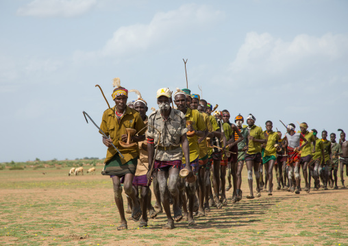 Men running in line with weapons during the proud ox ceremony in the Dassanech tribe, Turkana County, Omorate, Ethiopia