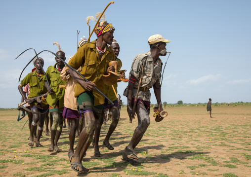 Men running in line with weapons during the proud ox ceremony in the Dassanech tribe, Turkana County, Omorate, Ethiopia