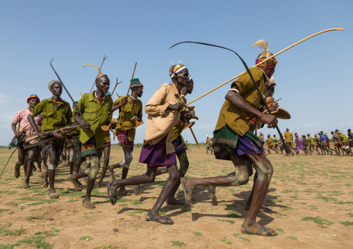 Men running in line with weapons during the proud ox ceremony in the Dassanech tribe, Turkana County, Omorate, Ethiopia