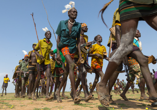 Men running in line with weapons during the proud ox ceremony in the Dassanech tribe, Turkana County, Omorate, Ethiopia