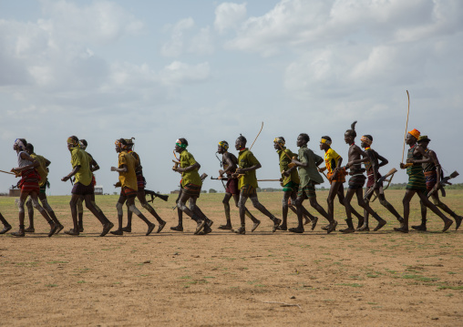 Men running in line with weapons during the proud ox ceremony in the Dassanech tribe, Turkana County, Omorate, Ethiopia