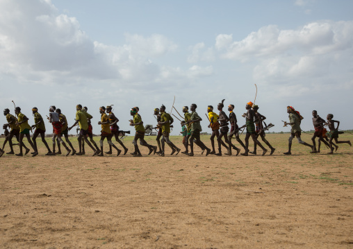 Men running in line with weapons during the proud ox ceremony in the Dassanech tribe, Turkana County, Omorate, Ethiopia